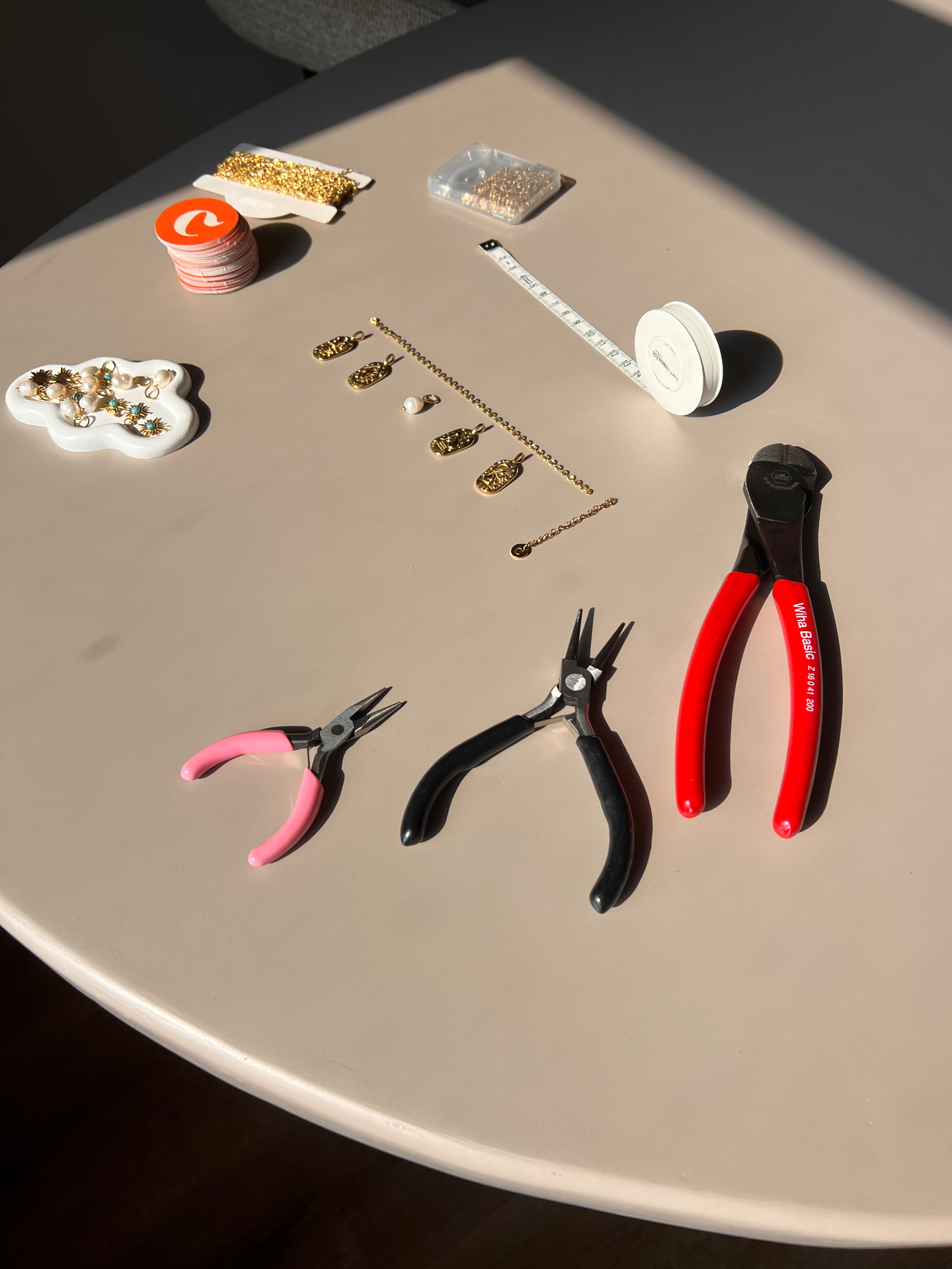 Werktafel met tangetjes, gouden kettingen en bedels waar de sieraden met de hand worden gemaakt in Groningen