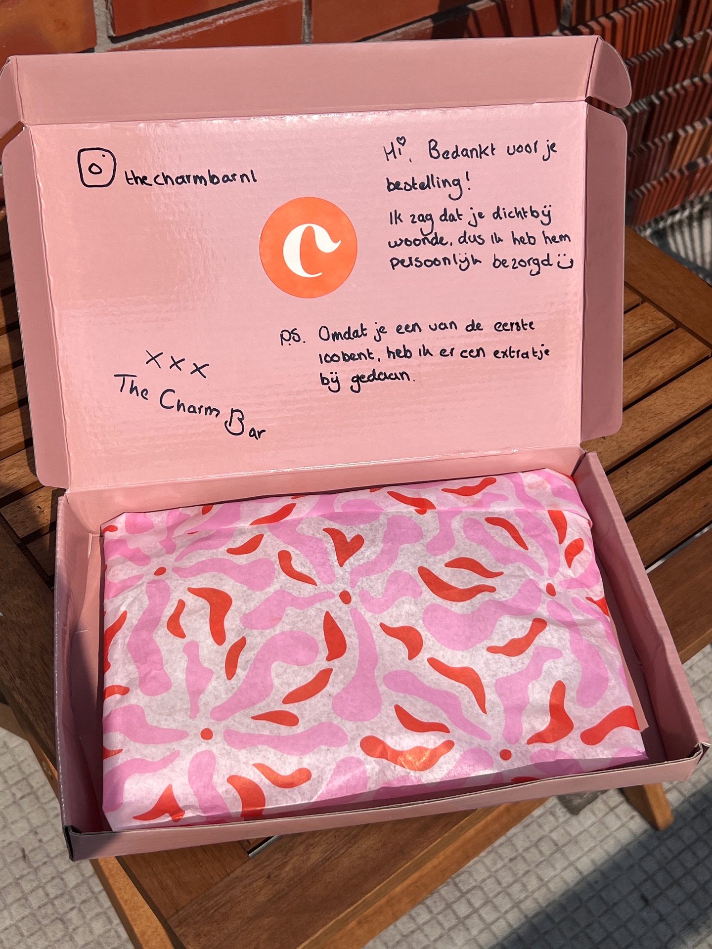Roze verzenddoosje van The Charm Bar met handgeschreven bedankkaartje en roze vloeipapier